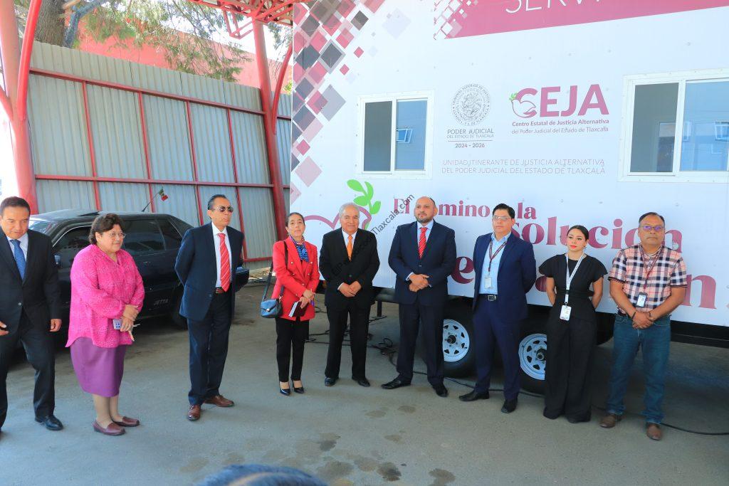 Grupo de personas en evento oficial frente a un autobús con logotipos y texto institucional en Tlaxcala, México.