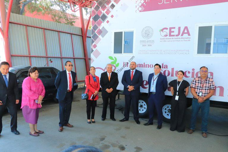 Grupo de personas en evento oficial frente a un autobús con logotipos y texto institucional en Tlaxcala, México.