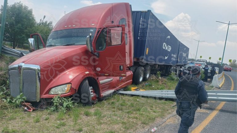 Accidente de tráiler en la autopista, vehículo volcado y daños en la vía, con presencia de personal de emergencia y policías en la escena.