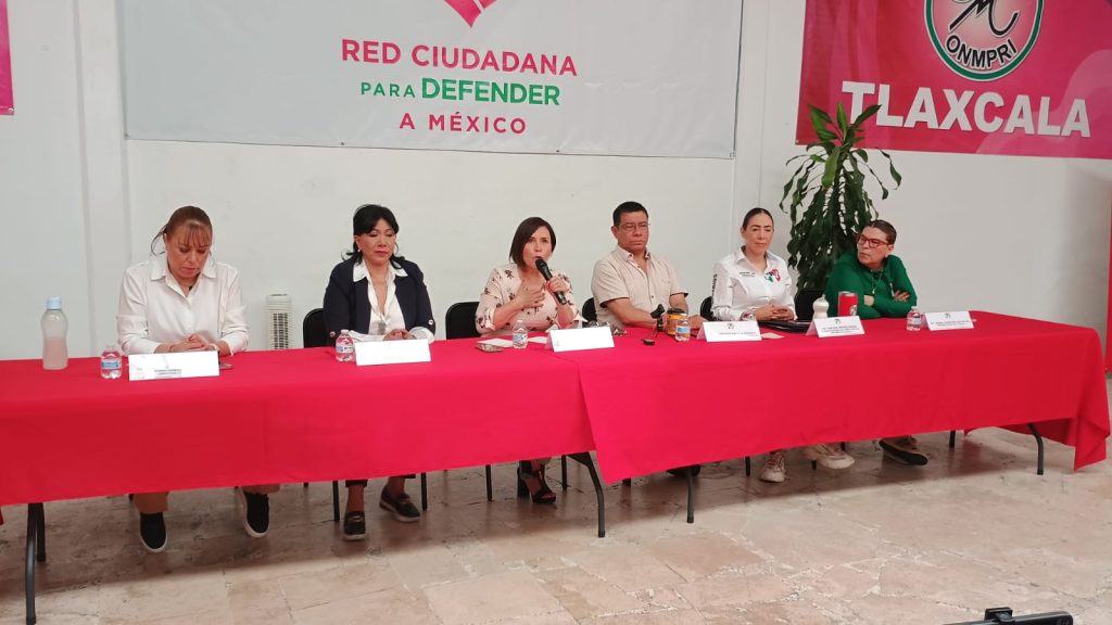 Panel de seis personas en una mesa con fondo de cartel que dice "Red Ciudadana para Defender a México" y bandera de Tlaxcala, participando en un evento político.