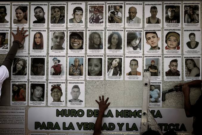 Retrato de varias fichas de personas desaparecidas en un muro con la leyenda "Muro de la memoria para la verdad y la justicia" en Tlaxcala, México.
