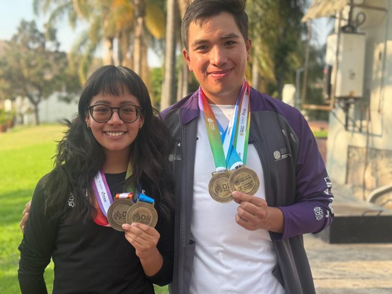 Dos jóvenes deportistas con medallas en un parque, celebrando sus logros en una competencia deportiva.
