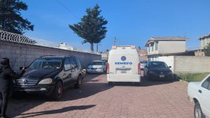 Detención policial en un estacionamiento en Tlaxcala, México, con varias unidades de vehículos y una persona tomando fotos, en un día soleado con cielo despejado y árboles en el fondo.