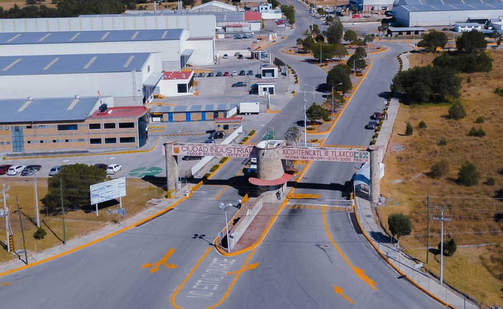 Entrada principal de la Ciudad Industrial de Tlaxcala con acceso controlado y señalización vial visible desde el aire.