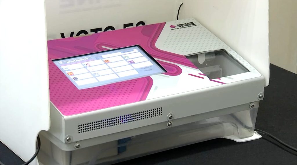 Voto electrónico en una casilla electoral, con una pantalla táctil y equipo de votación digital, utilizado para facilitar el proceso electoral en México.