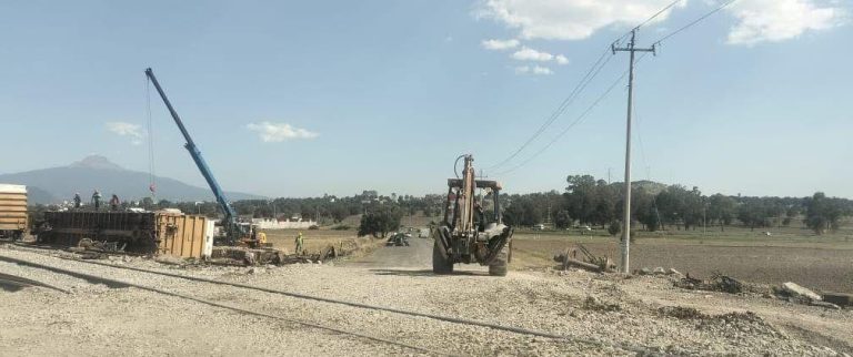 Cargador y maquinaria en una obra de construcción en un campo abierto con cielo despejado y líneas eléctricas, en Tlaxcala, México, durante el día.