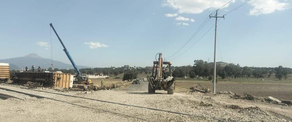 Cargador y maquinaria en una obra de construcción en un campo abierto con cielo despejado y líneas eléctricas, en Tlaxcala, México, durante el día.