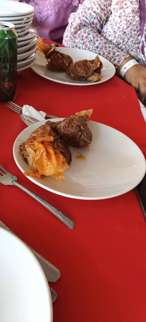 Platos de carne y papas fritas en una mesa con fondo de platos y bebidas, en un ambiente de comida casera.