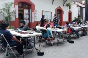 Partida de ajedrez al aire libre con varios jugadores y espectadores en una calle de Tlaxcala, México, en un evento comunitario o torneo informal.