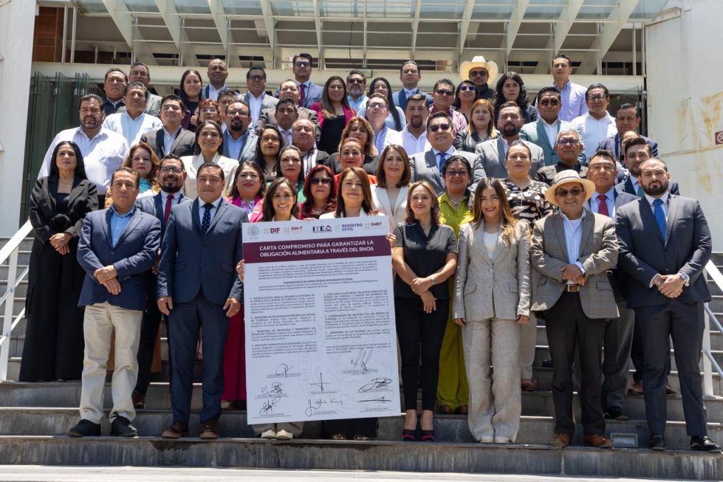 Grupo de profesionales y funcionarios en una ceremonia oficial, sosteniendo un documento importante frente a un edificio público en Tlaxcala, México.