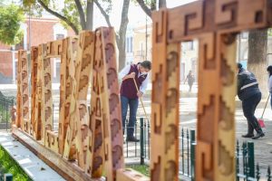 Personas limpiando y cuidando un espacio público con letras decorativas de madera en Tlaxcala, México.