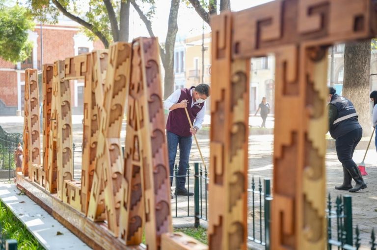 Personas limpiando y cuidando un espacio público con letras decorativas de madera en Tlaxcala, México.