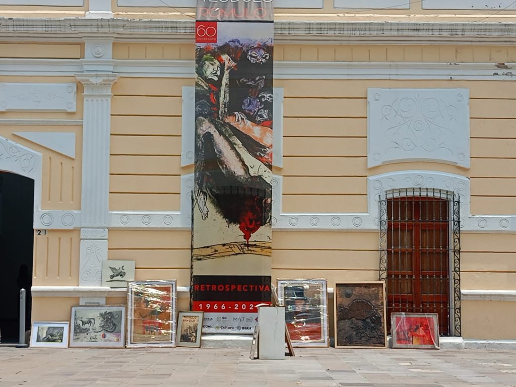 Exposición de arte en un edificio histórico con varias obras enmarcadas en el suelo.