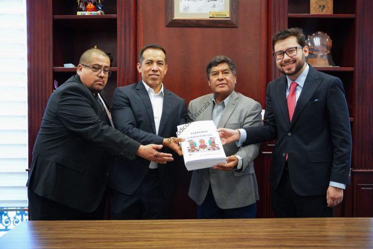 Cuatro hombres en una reunión formal intercambian un documento en una oficina con estanterías de madera.