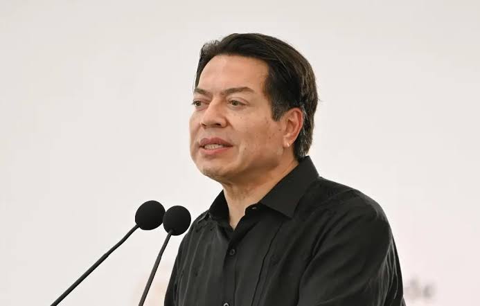 Un hombre hablando en un micrófono durante una conferencia o evento formal.